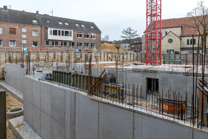 Ściany fundamentowe z wystającym zbrojeniem, w tle żuraw