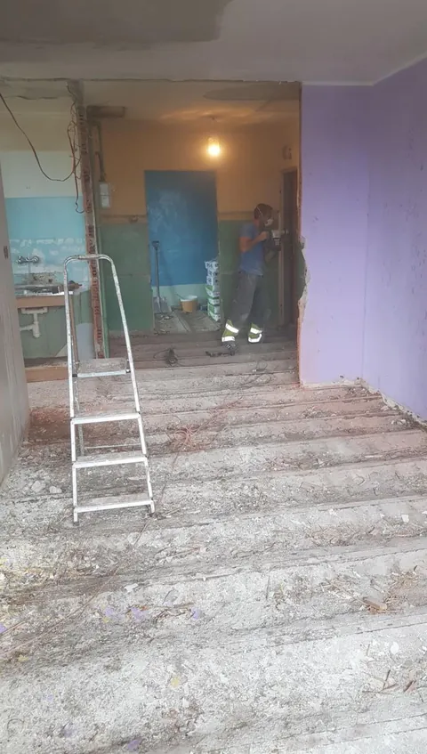 Mieszkanie w trakcie remontu: skute ściany, stare instalacje w łazience, pracownik przy wyburzeniu