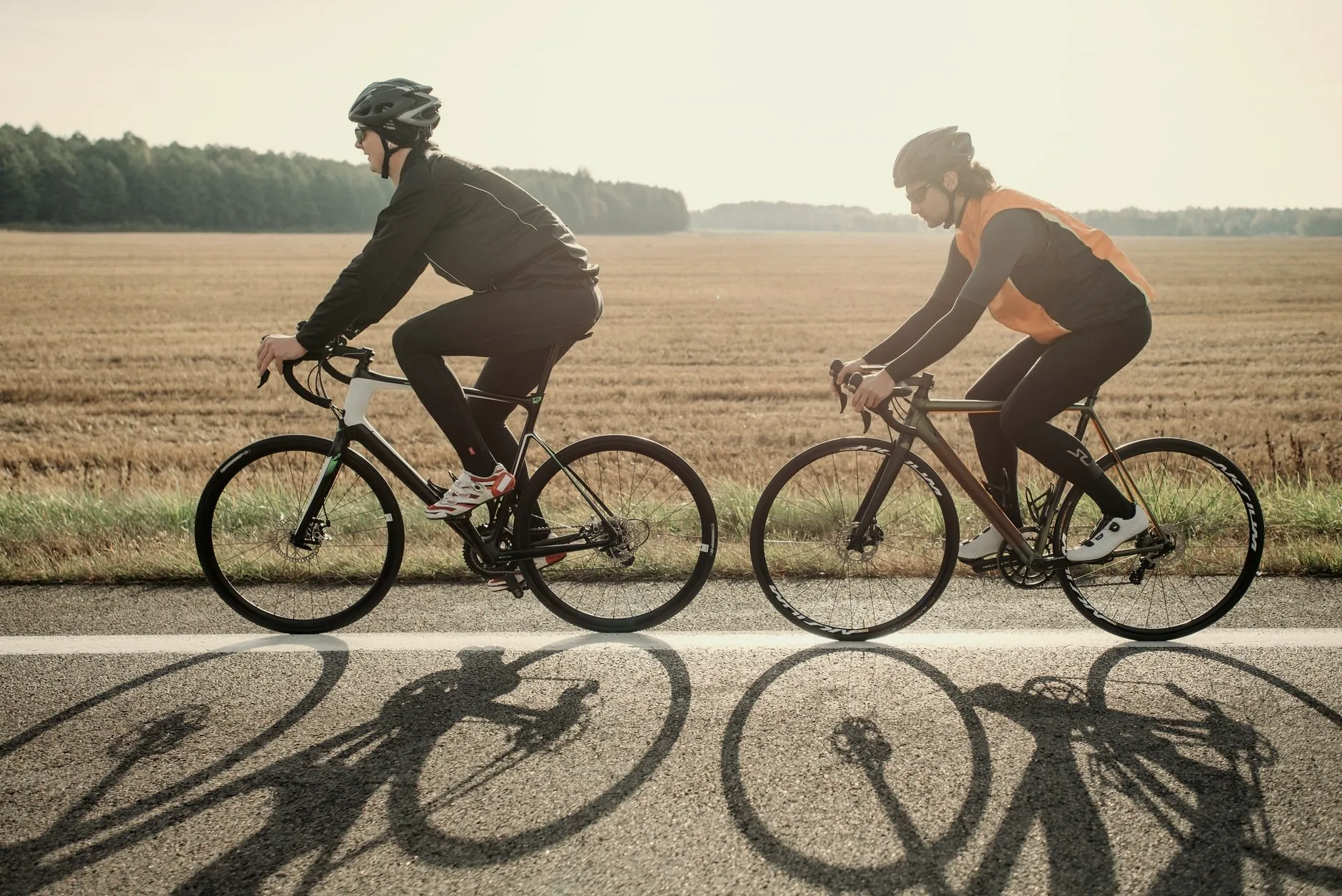 Dwoje rowerzystów na szosie wśród pól